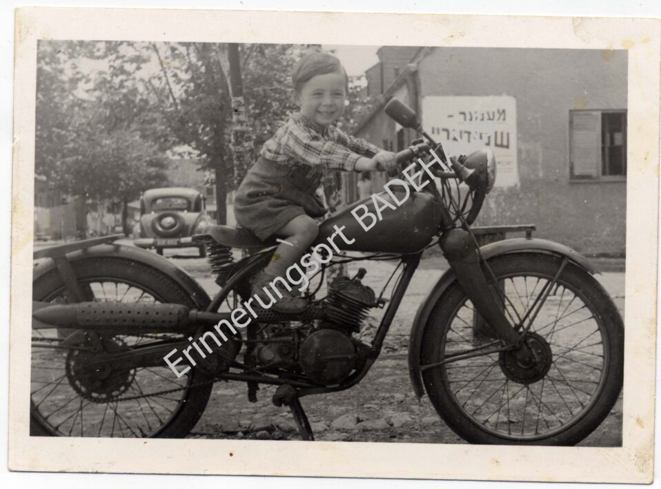 Ein Kind in Föhrenwald auf einem Motorrad, 1951.